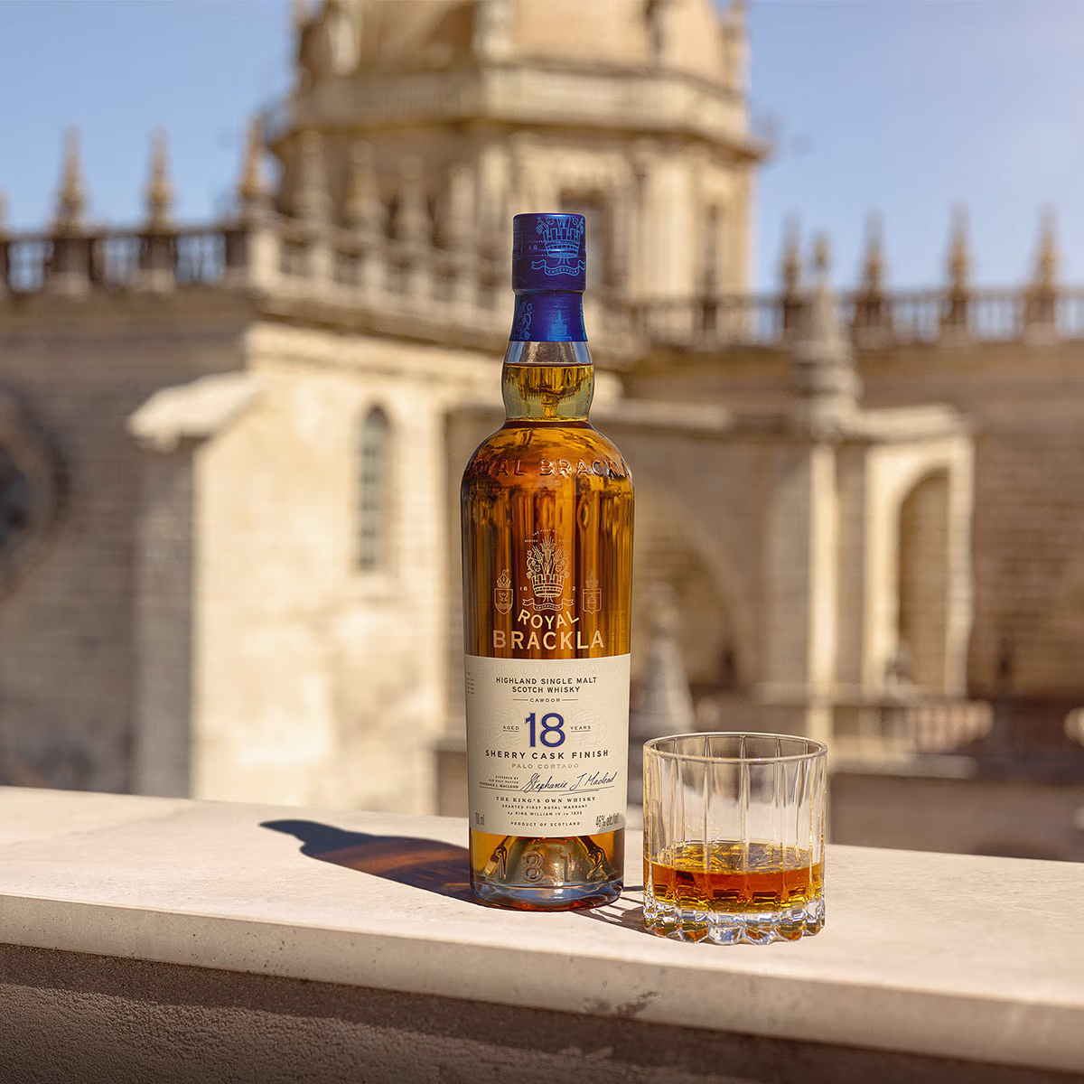 Bottle of Royal Brackla 18 Year Sherry Cask Finish Highland Single Malt Scotch Whisky beside a rocks glass of amber whisky.