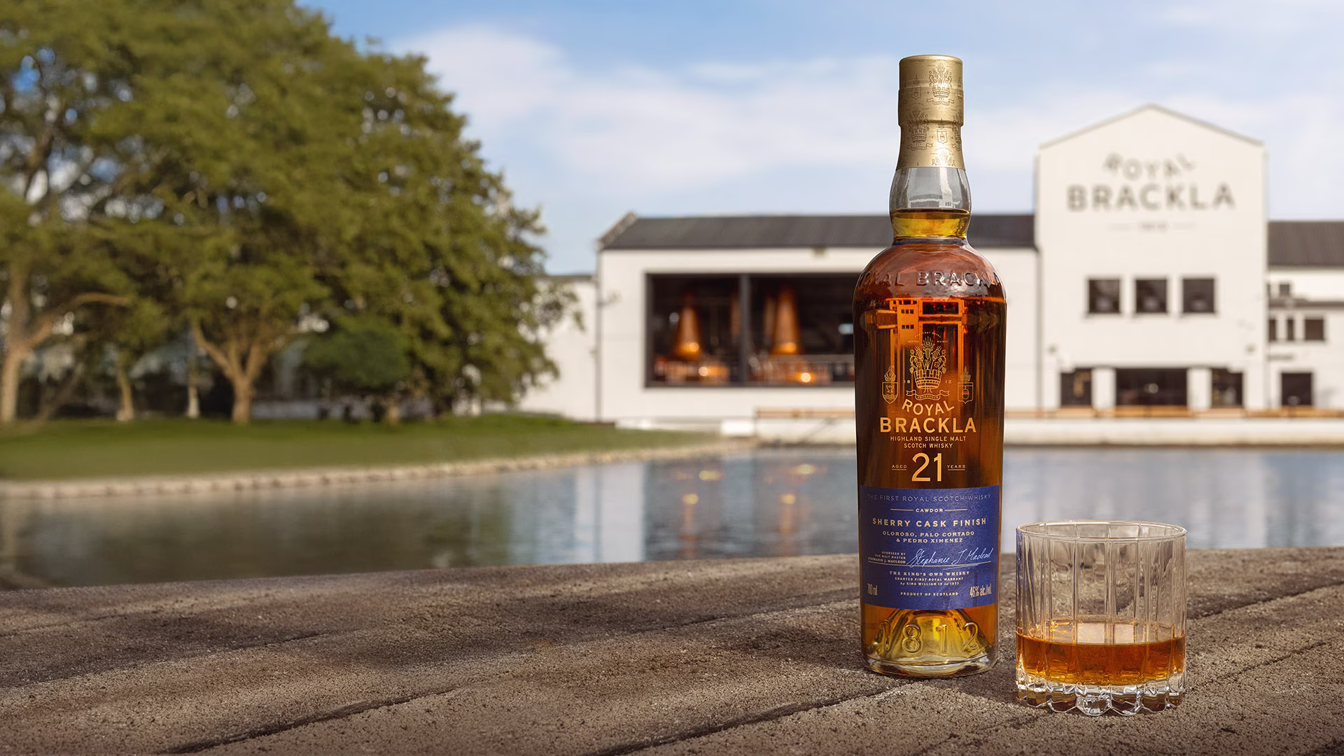Royal Brackla 21-year-old Highland Single Malt Scotch Whisky bottle with blue and gold label next to a glass of amber whisky.