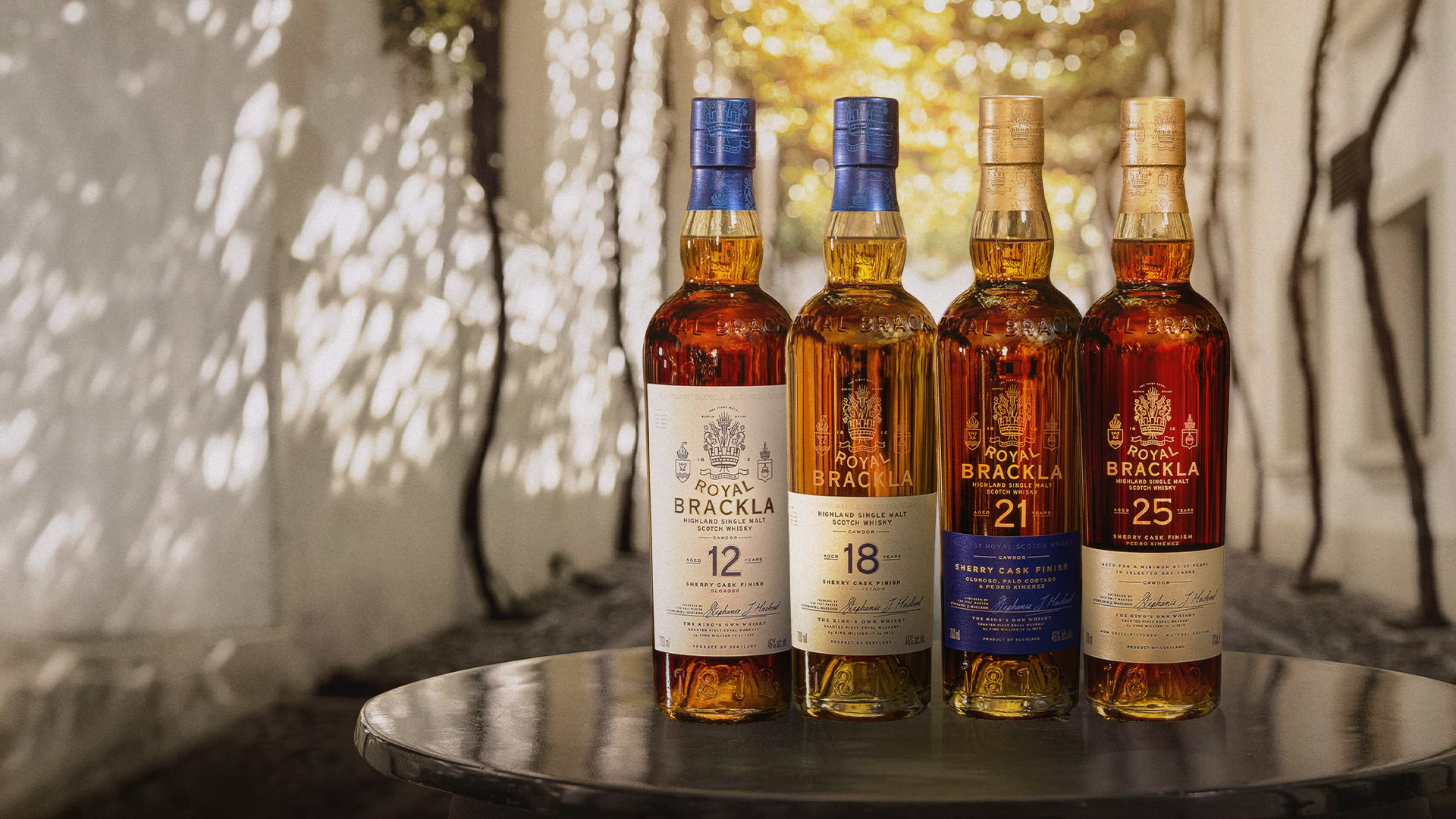 Four Royal Brackla Highland Single Malt Scotch Whisky bottles displaying varying amber liquid colors, arranged in a row.